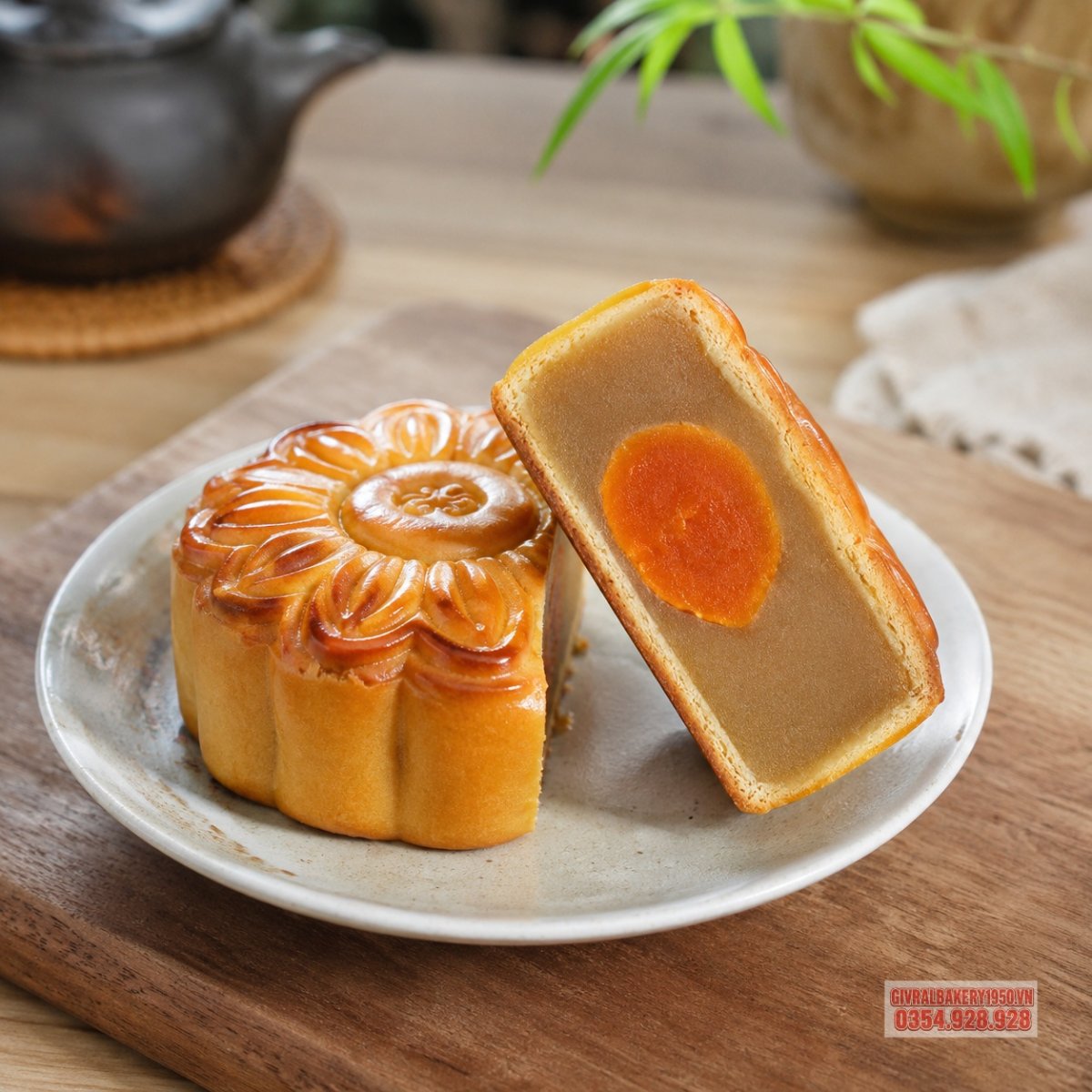 Một chiếc bánh trung thu Givral được cắt đôi, lộ ra lớp nhân hạt sen và trứng muối bùi béo, vỏ bánh mỏng mịn, ánh sáng tự nhiên làm nổi bật độ tươi của bánh.